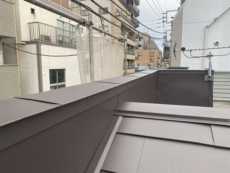 屋根とパラペットの接合部、壁際からの雨水の侵入を防ぐため、L形の板金部材を取付けてから壁を張っています
